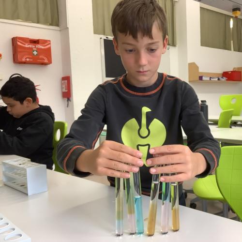 Kind mit farbigen Flüssigkeitsschichten in mehreren Reagenzgläsern