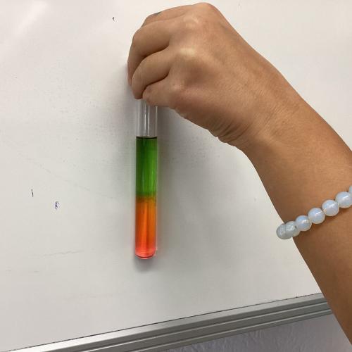 Kind mit Reagenzglas, in dem sich übereinander geschichtete Flüssigkeiten befinden.