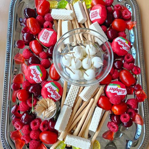Rot-weiß-rote Snack-Platte mit Früchten, Käse und Grissini.