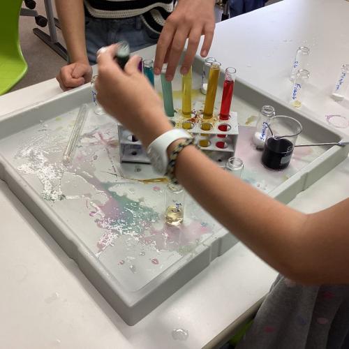 Kinder mischen Lösungen zusammen, um verschiedene Farben in Reagenzgläsern zu erzeugen.