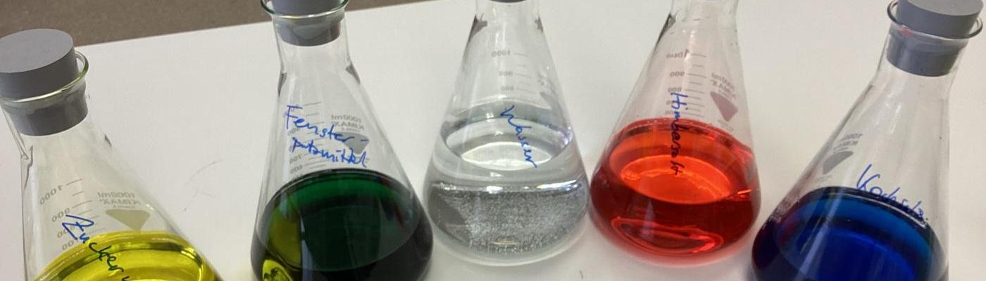 Fünf Erlenmeyerkolben mit farbigen Lösungen