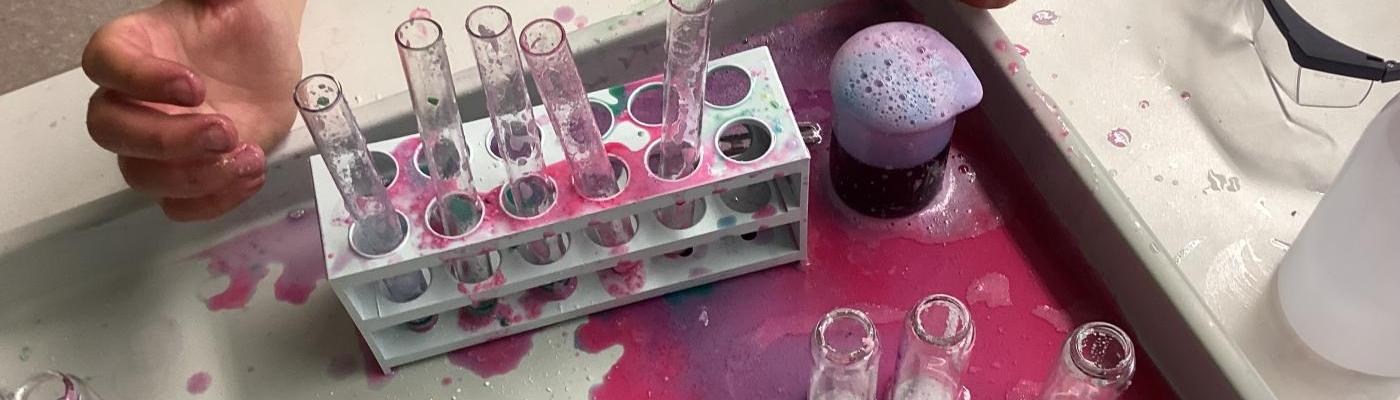 Laborplatz mit rot-violett-grüner Flüssigkeit am Tisch