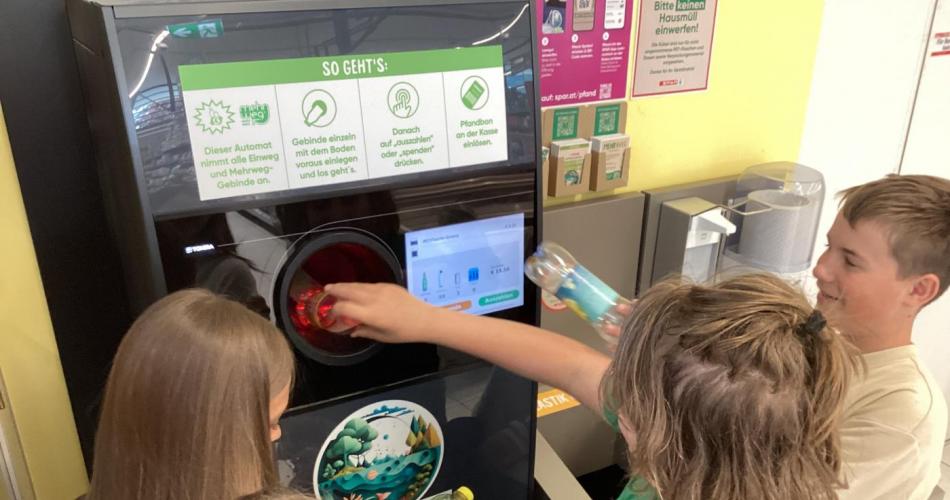 Kinder der 2c füttern den Pfandautomaten mit selbstgesammelten PET-Flaschen.